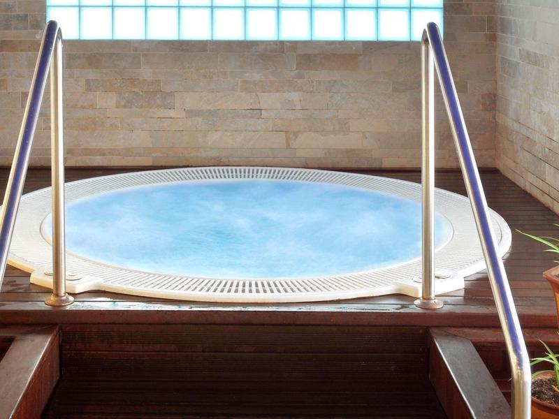 Jacuzzi redondo con barandillas metálicas y escaleras en un interior moderno.