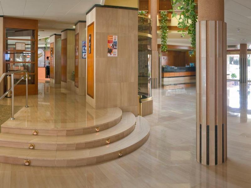 Amplia área abierta de vestíbulo de hotel con suelo de mármol y escaleras, decoración moderna.