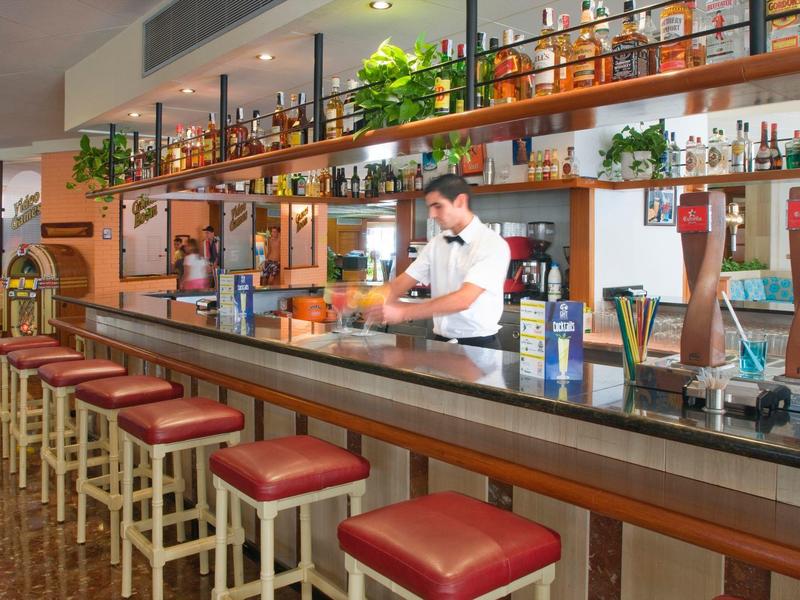 Bar moderna con taburetes rojos y camarero en un hotel