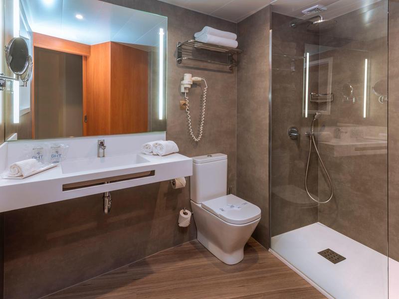 Baño moderno con ducha, inodoro y lavabo en tonos cálidos de marrón y beige.