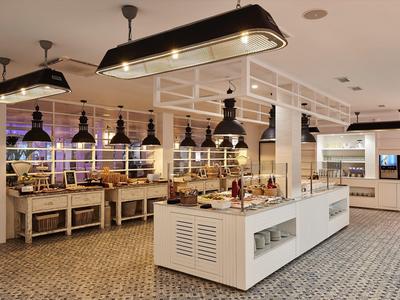 Sala de desayuno moderna con isla de buffet y lámparas colgantes en un hotel.