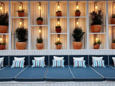 Cómodas tumbonas frente a una pared decorativa con plantas y luz cálida.