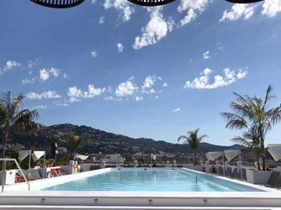 Piscina moderna con vista a colinas y cielo, cubierta por elegantes cestas.