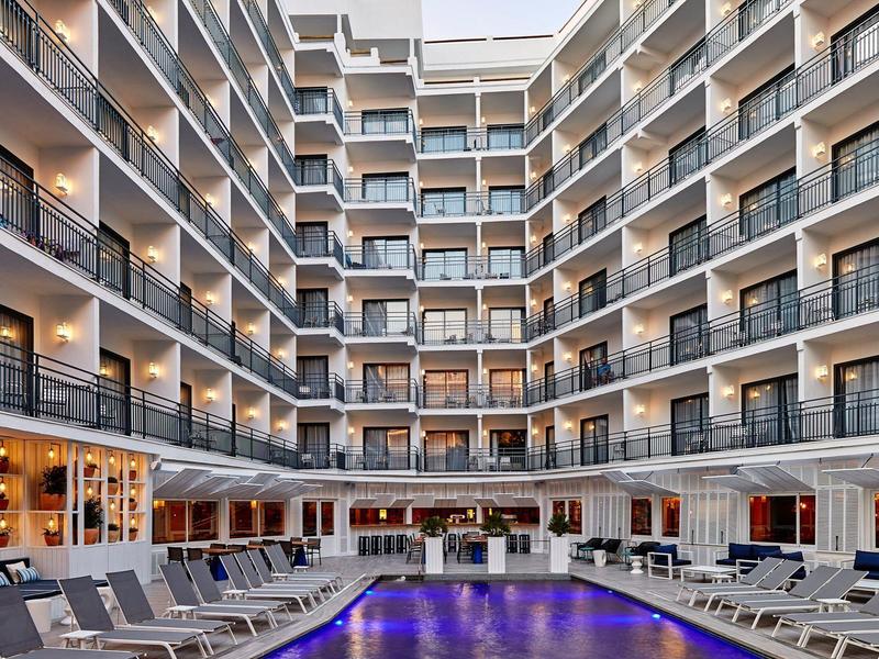 Hotel con gran patio interior y piscina iluminada, rodeado de balcones de varios pisos.