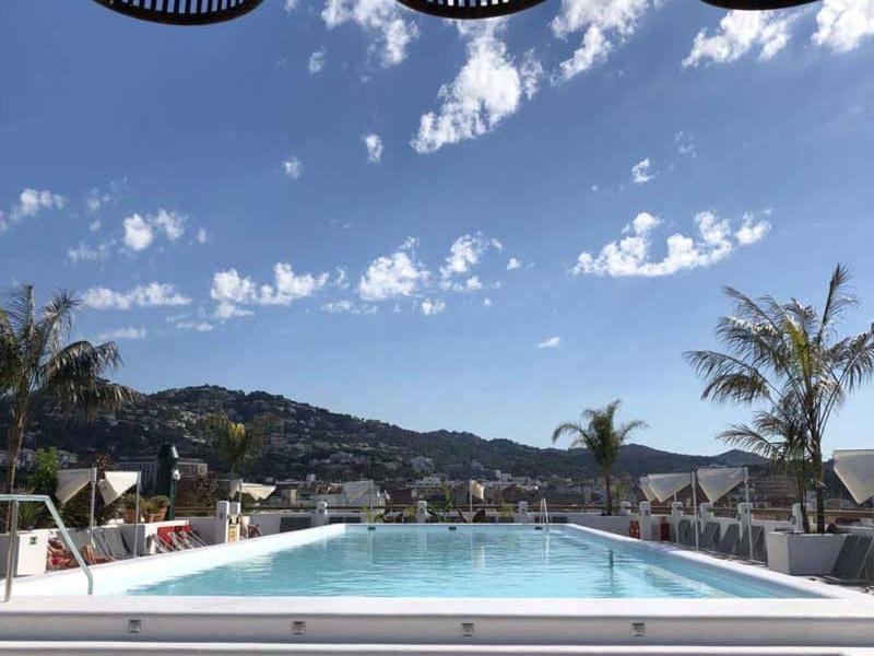 Piscina moderna con vista a colinas y cielo, cubierta por elegantes cestas.