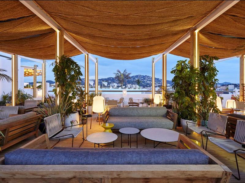 Elegante terraza en la azotea con muebles modernos y vista urbana al atardecer.