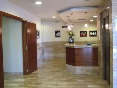 Modern hotel reception with front desk, flowers, and artwork on the walls.