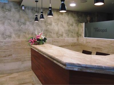 Modern reception area with marble surfaces and flowers, illuminated by multiple pendant lights.