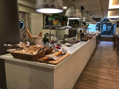 Buffet with various breads, cold cuts, and utensils in a modern restaurant