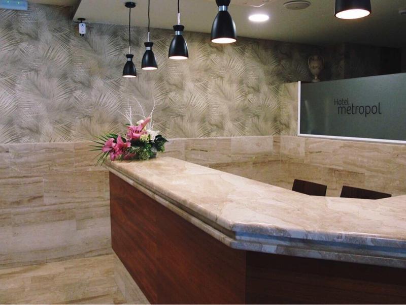 Modern reception area with marble surfaces and flowers, illuminated by multiple pendant lights.