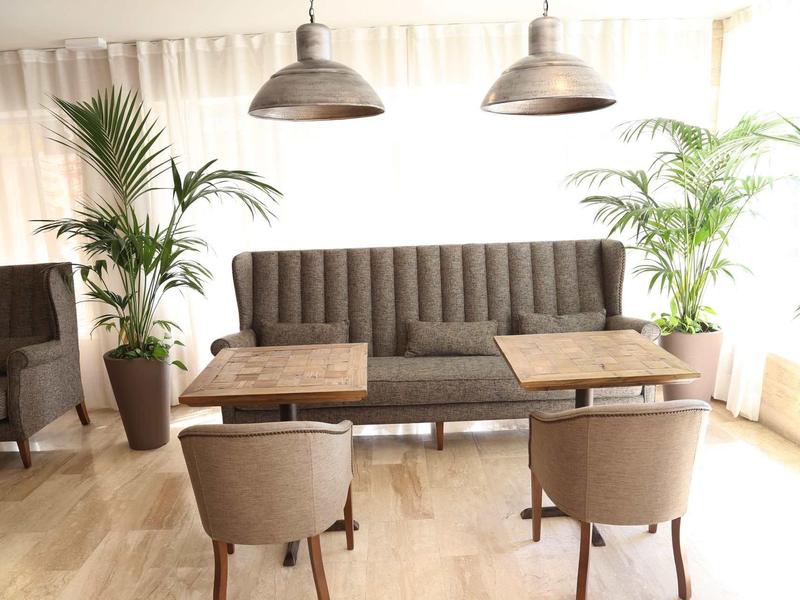 Cozy seating area with sofa, chairs, and tables next to large windows in a bright room.