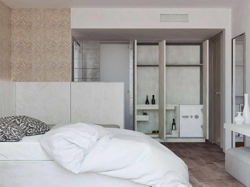 Modern bedroom with white bed, wall-mounted TV, and minimalist decor