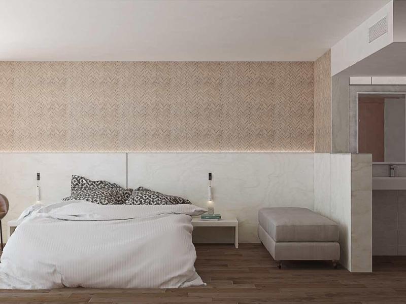 Modern bedroom with large bed, armchair, and access to a bathroom with glass shower.