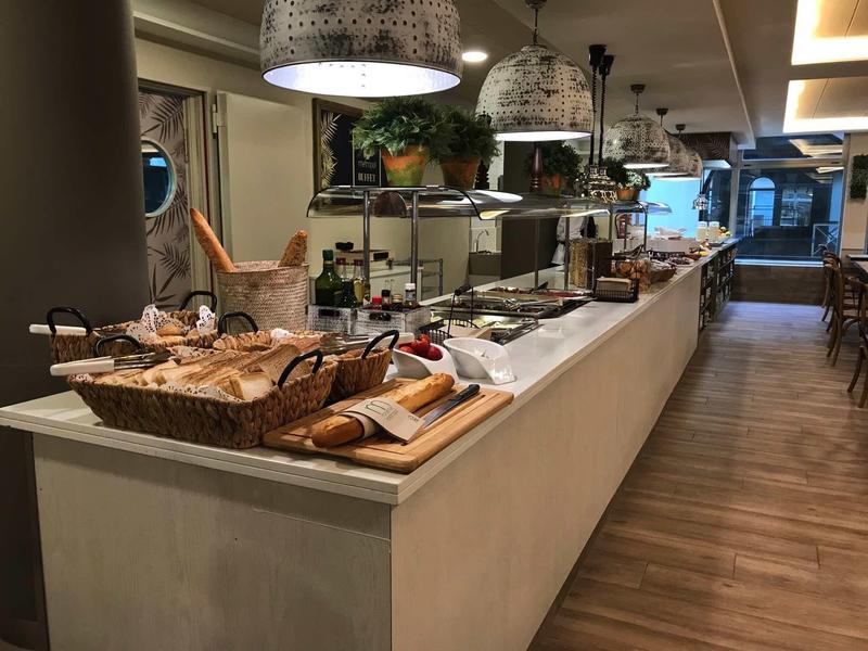 Buffet with various breads, cold cuts, and utensils in a modern restaurant