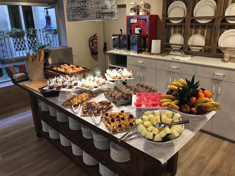 A buffet with assorted cakes and fruit in a cozy restaurant with wooden flooring.