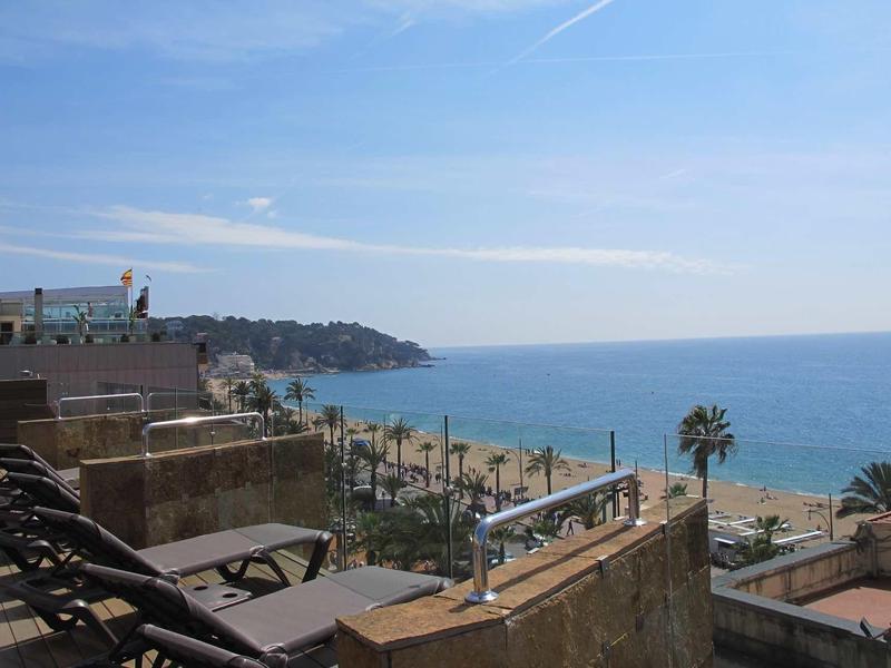 Balcony with lounge chairs overlooking the sea under a clear sky