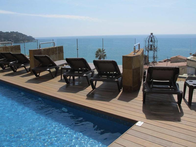 Poolside loungers with sea view and partly cloudy sky in the background.