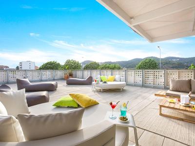 Spacious rooftop terrace with cozy sofas, colorful cushions, and a clear blue sky.