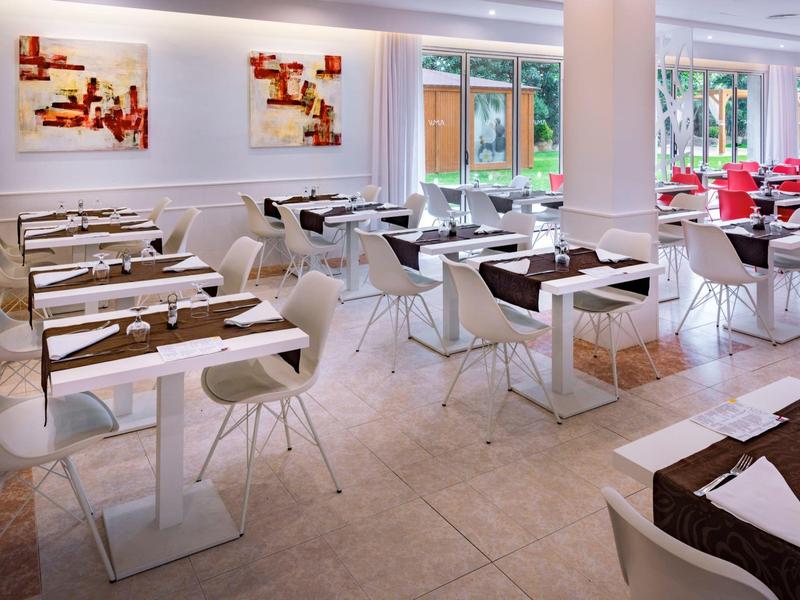 Bright and modern restaurant with white furniture, large windows, and abstract wall art.