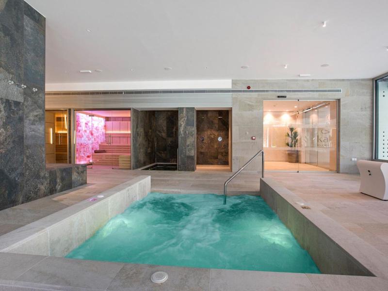 Indoor spa area with a bubbling hot tub, stone walls, and soft lighting for relaxation.
