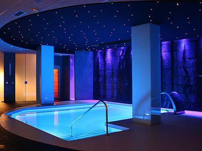 Nowoczesny, oświetlony basen z relaksującą niebiesko-fioletową atmosferą.