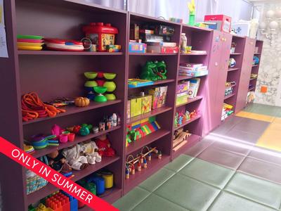 Kolorowe regały z zabawkami i książkami w jasnej strefie dziecięcej