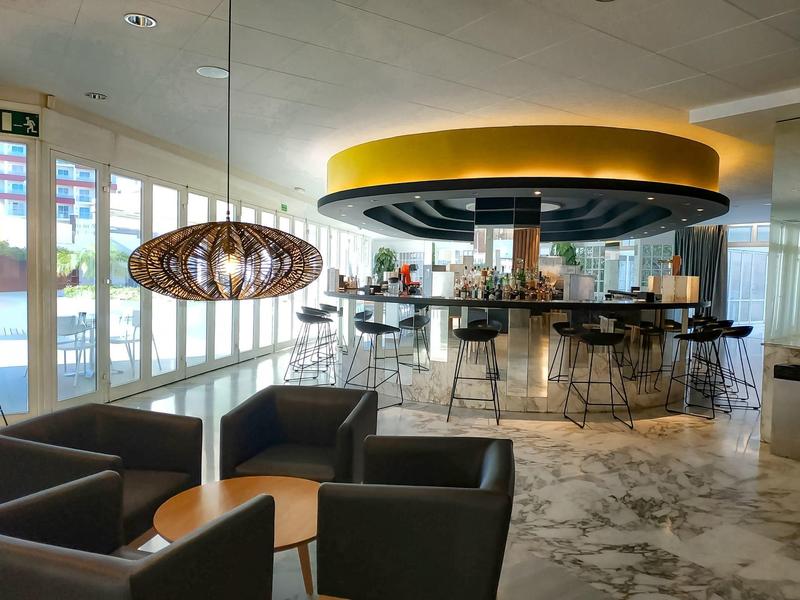 Nowoczesny bar hotelowy z stylowymi miejscami do siedzenia i dużymi oknami w świetle dziennym.