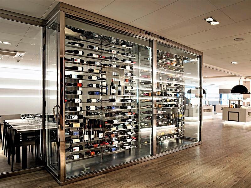 Nowoczesny pokój na wino ze szklanymi ścianami w stylowej restauracji hotelowej z drewnianą podłogą.