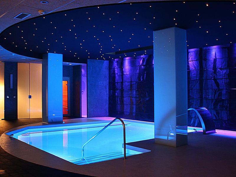Nowoczesny, oświetlony basen z relaksującą niebiesko-fioletową atmosferą.