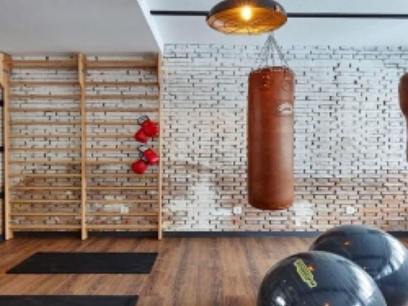 Sala fitness con sacco da boxe, palle da ginnastica, tappetini e parete da arrampicata in legno