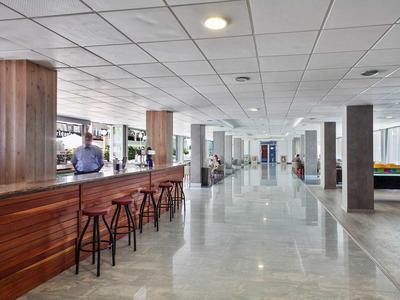 Ampia hall d'albergo luminosa con bancone bar e posti a sedere.