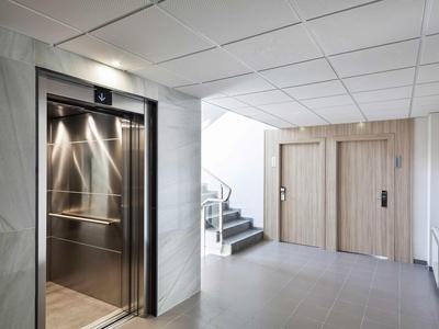 Corridoio d'hotel moderno con ascensore aperto e scala che conduce alle camere.