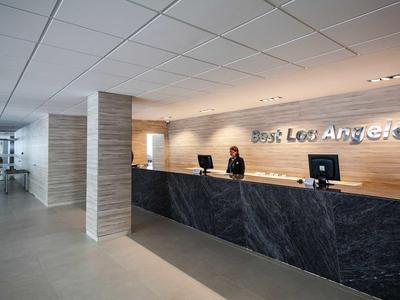 Reception d'hotel moderna con banco in marmo scuro e personale cordiale.