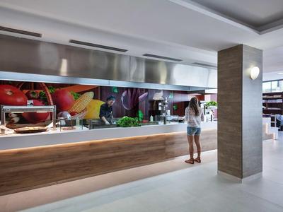 Sala da pranzo moderna in hotel con buffet self-service e decorazioni alimentari fresche.