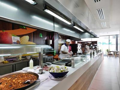 Area buffet con vari piatti e chef dietro il banco in un ristorante luminoso.