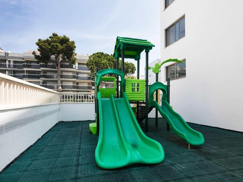 Area giochi verde con scivoli sulla terrazza di un hotel.