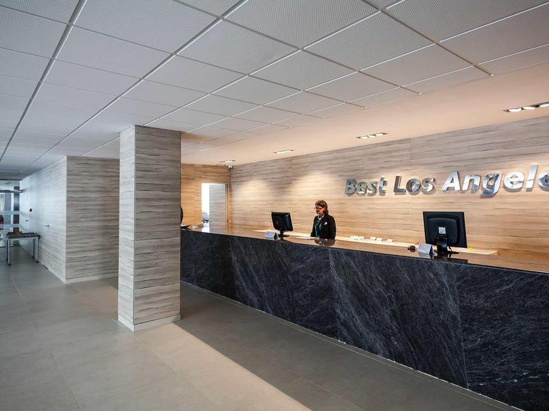 Reception d'hotel moderna con banco in marmo scuro e personale cordiale.