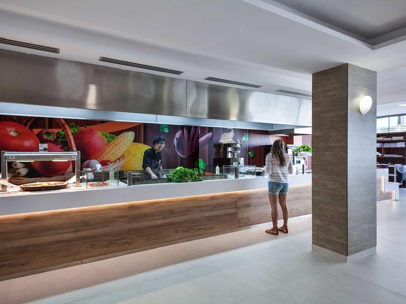 Sala da pranzo moderna in hotel con buffet self-service e decorazioni alimentari fresche.