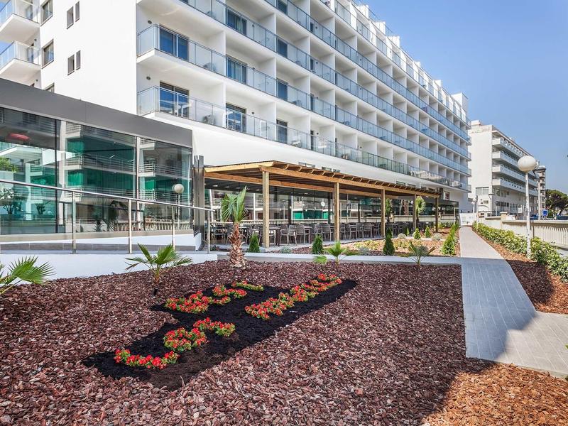 Hotel moderno con grandi balconi e aree esterne sotto un cielo sereno