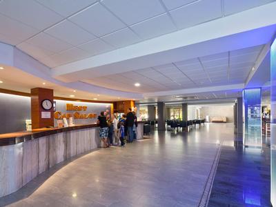 Luminoso atrio dell'hotel con reception, area salotto e design moderno.