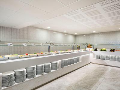 Clean, modern buffet area with plates and food trays in bright, tiled room.