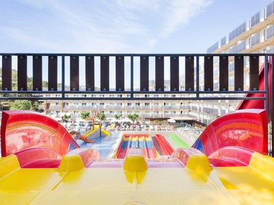 View from the top of colorful water slides at a sunny water park with pools and lounging area.
