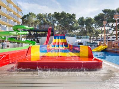 Colorful water slides and splash pads at a hotel pool with trees and balconies in the background