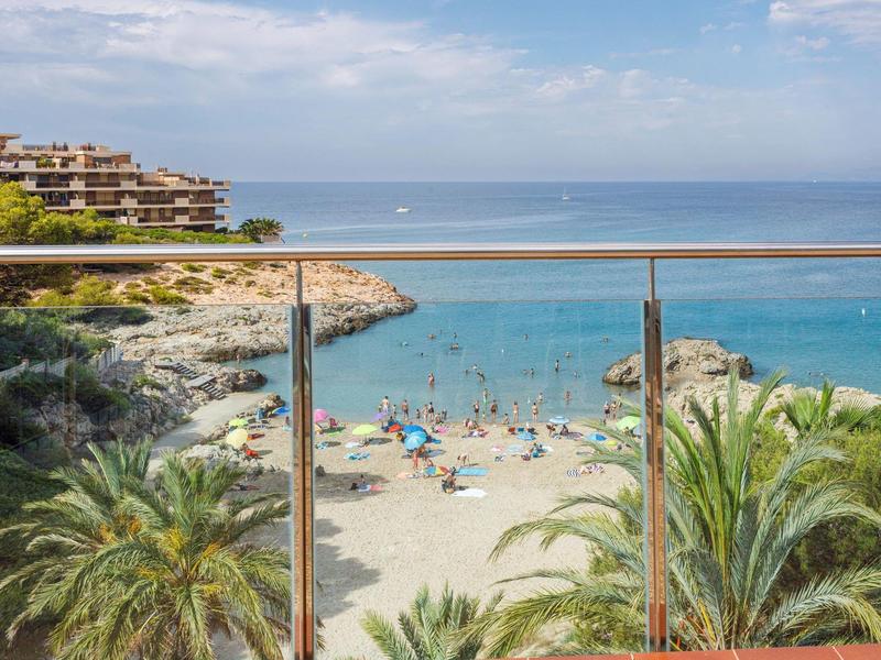 Beach view with turquoise sea, palm trees, and people enjoying the sand and water.