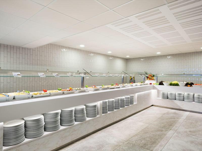 Clean, modern buffet area with plates and food trays in bright, tiled room.