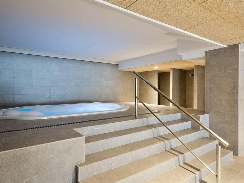 Modern indoor jacuzzi area with steps, handrails, and neutral tones.