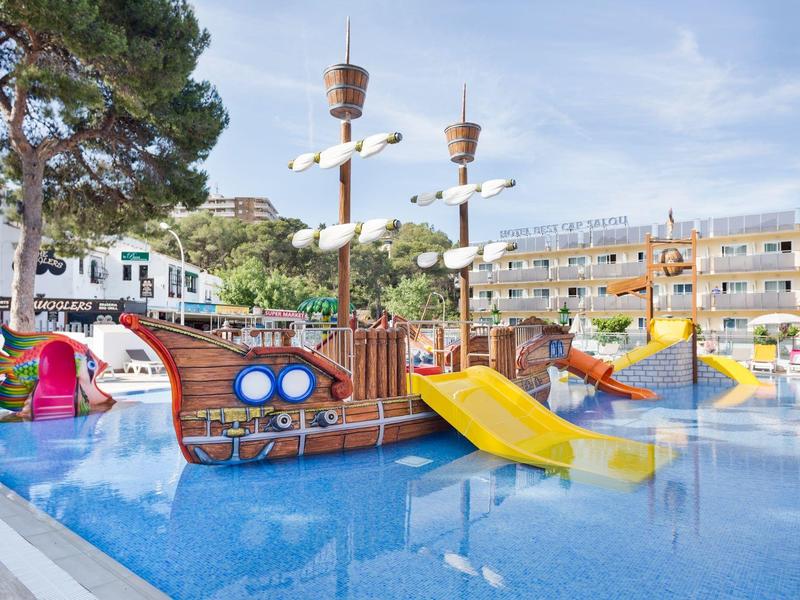 Outdoor water playground with pirate ship, slides, and colorful play structures in a hotel pool area.