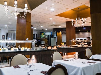 Elegancka restauracja z białymi obrusami, drewnianymi meblami i nowoczesnym oświetleniem.
