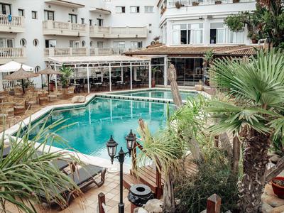 Zewnętrzny basen hotelowy z leżakami i palmami na dziedzińcu.