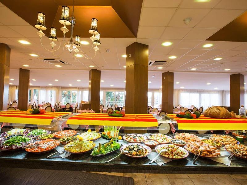 Buffet with a variety of dishes displayed in a spacious dining area with chandeliers.